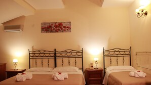 A hotel room with two beds, each with a lamp, a painting on the wall, and a small bedside table. - Marchese Sala (Agrigento)