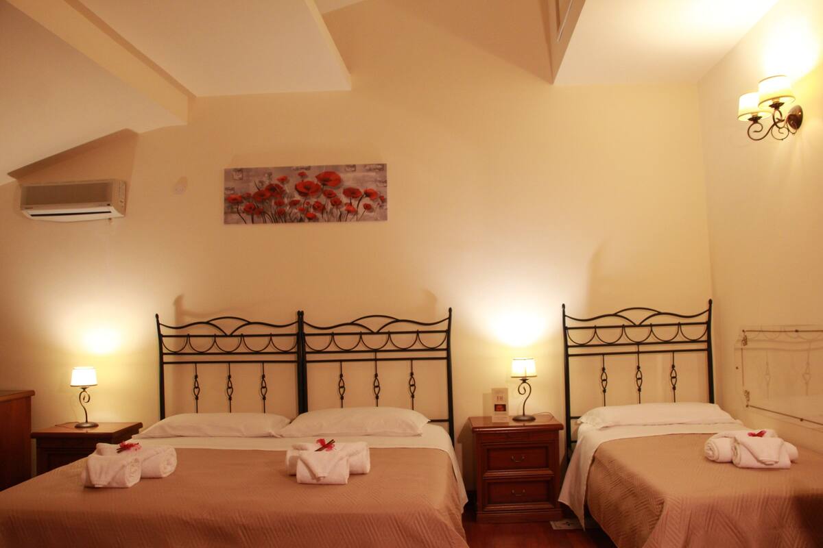 Habitación de hotel con dos camas, cada una con una lámpara, un cuadro en la pared y una mesita de noche.