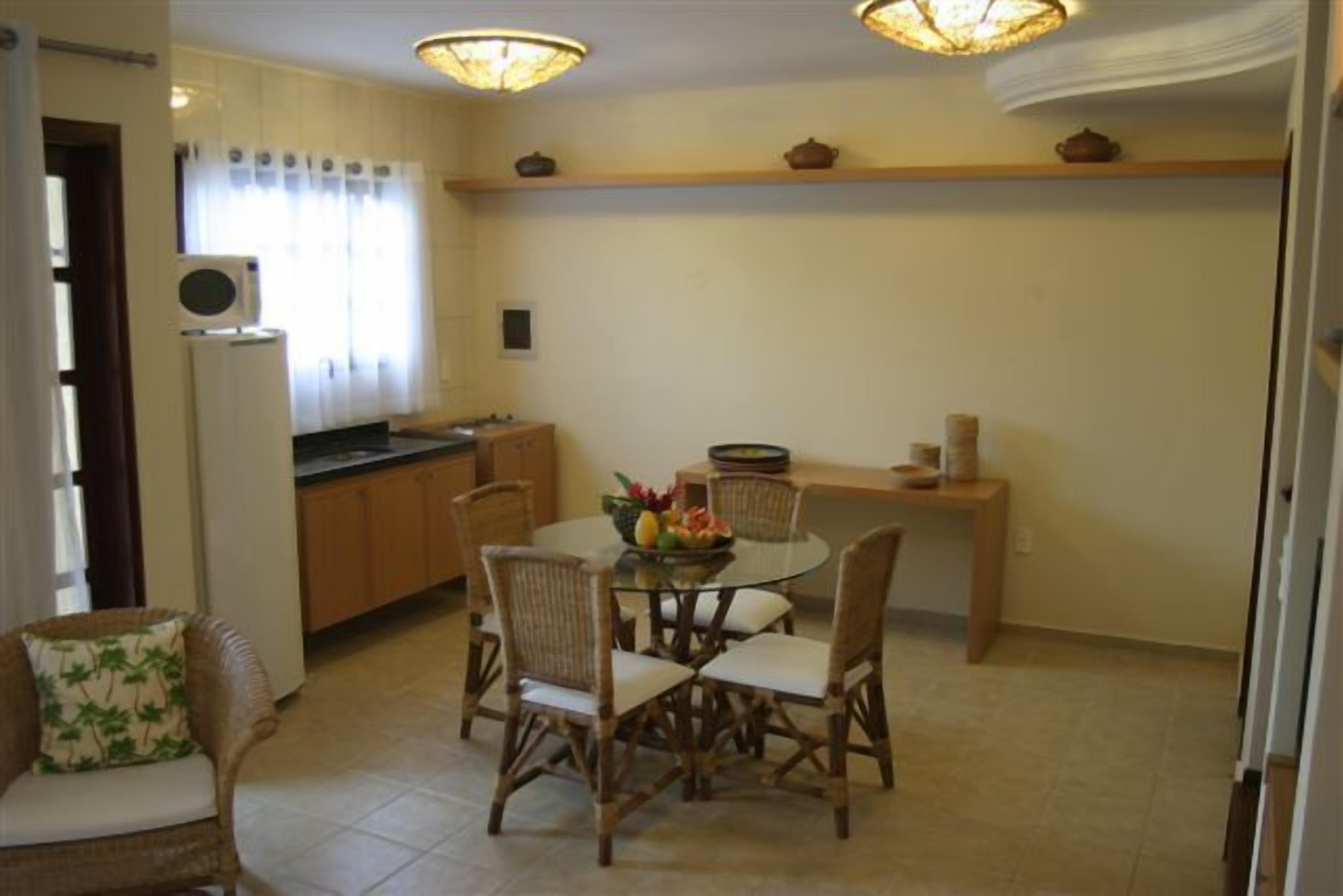 A compact kitchen with a dining area, featuring a round table, wicker chairs, and a built-in stove.