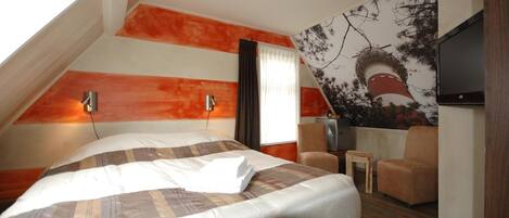 Een hotelkamer met een groot bed, een flatscreen-tv, een tafeltje en een stoel.