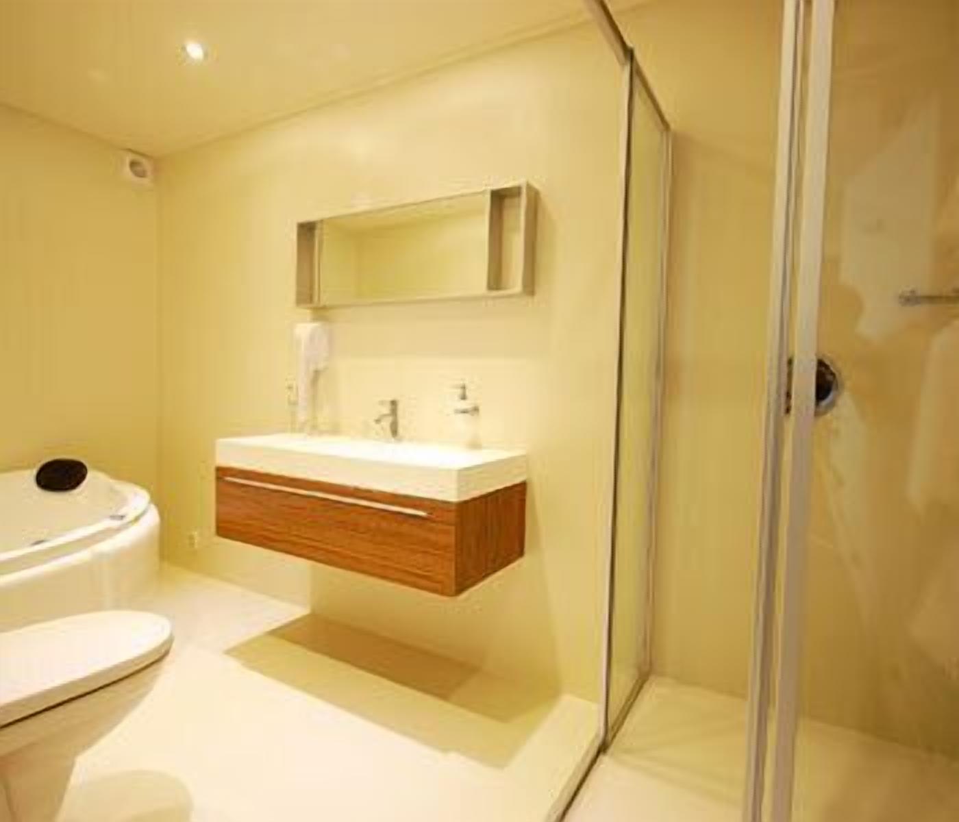 A modern bathroom with a glass shower enclosure, a wooden vanity, and a white toilet.