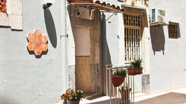 A narrow street with a building featuring a tiled entrance, a metal gate, and potted plants. - B&B Garibaldi Catania (Catania)
