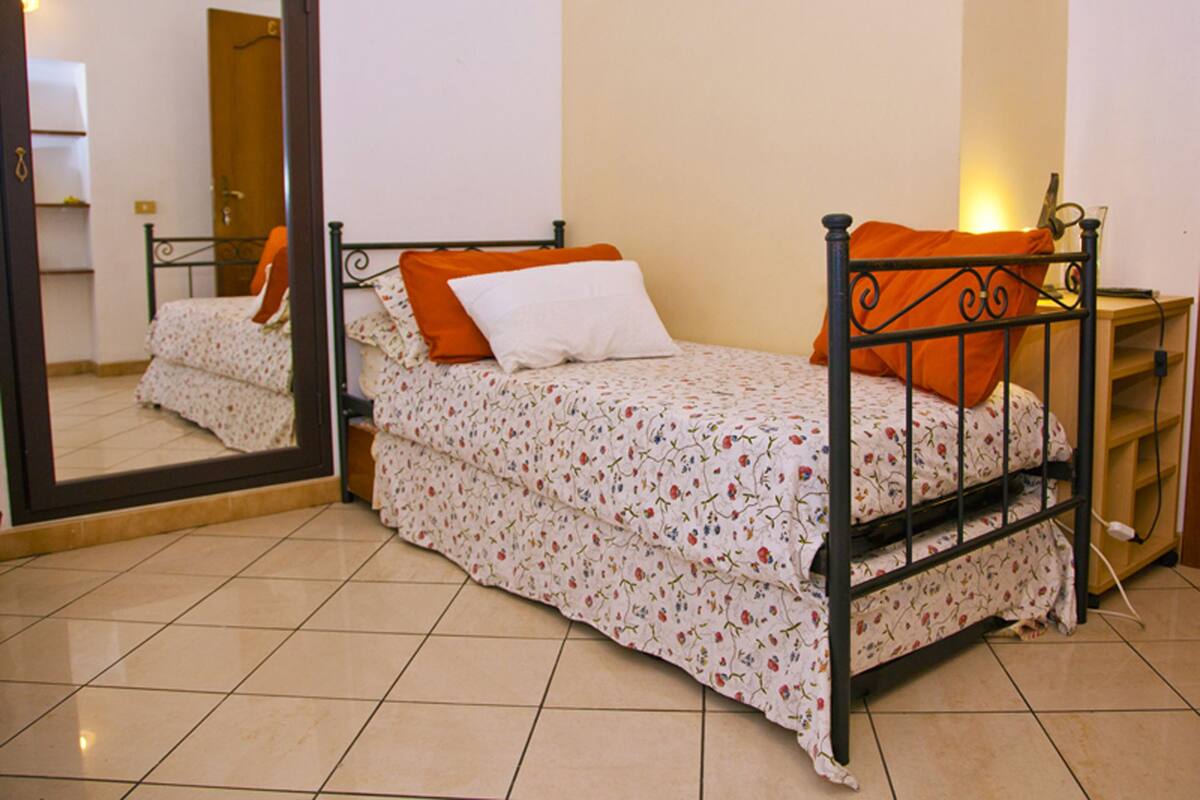Ein Schlafzimmer mit Bett, Nachttisch, Spiegel und Kleiderschrank.