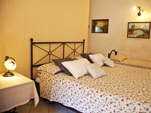 A bedroom with two beds, a nightstand, and wall-mounted lamps. - B&B Garibaldi Catania (Catania)