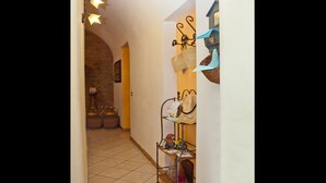 A narrow hallway with tiled flooring, a metal rack with hats and bags, and a wall-mounted clock. - B&B Garibaldi Catania (Catania)