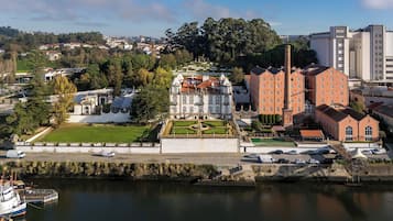 A historic building with a formal garden, a large central fountain, and a river in the foreground.