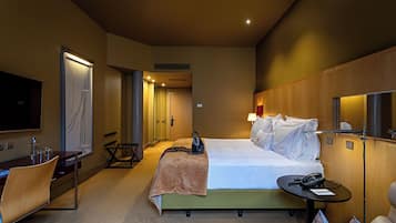 Una habitación de hotel con cama, mesita de noche, silla, escritorio, televisión y obras de arte.