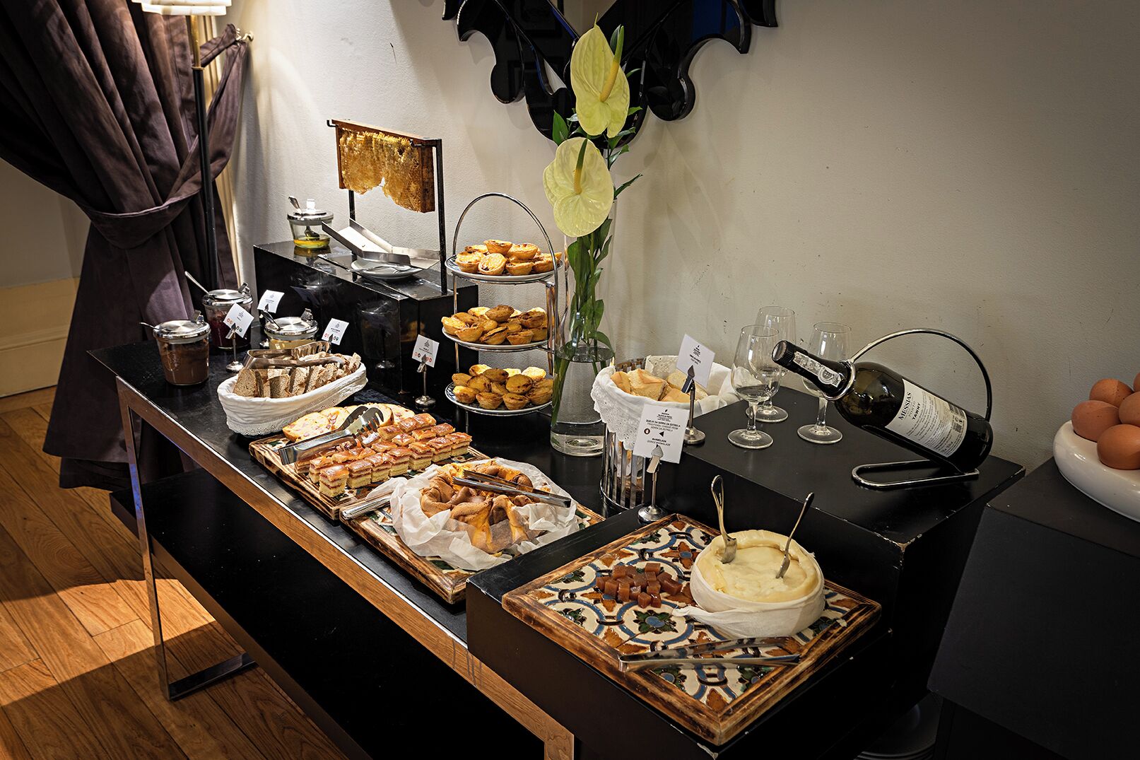 Une table de buffet avec divers plats, une bouteille de vin et un vase rempli de fleurs jaunes.