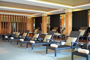 A hotel lobby with rows of lounge chairs, wooden columns, and a modern design.