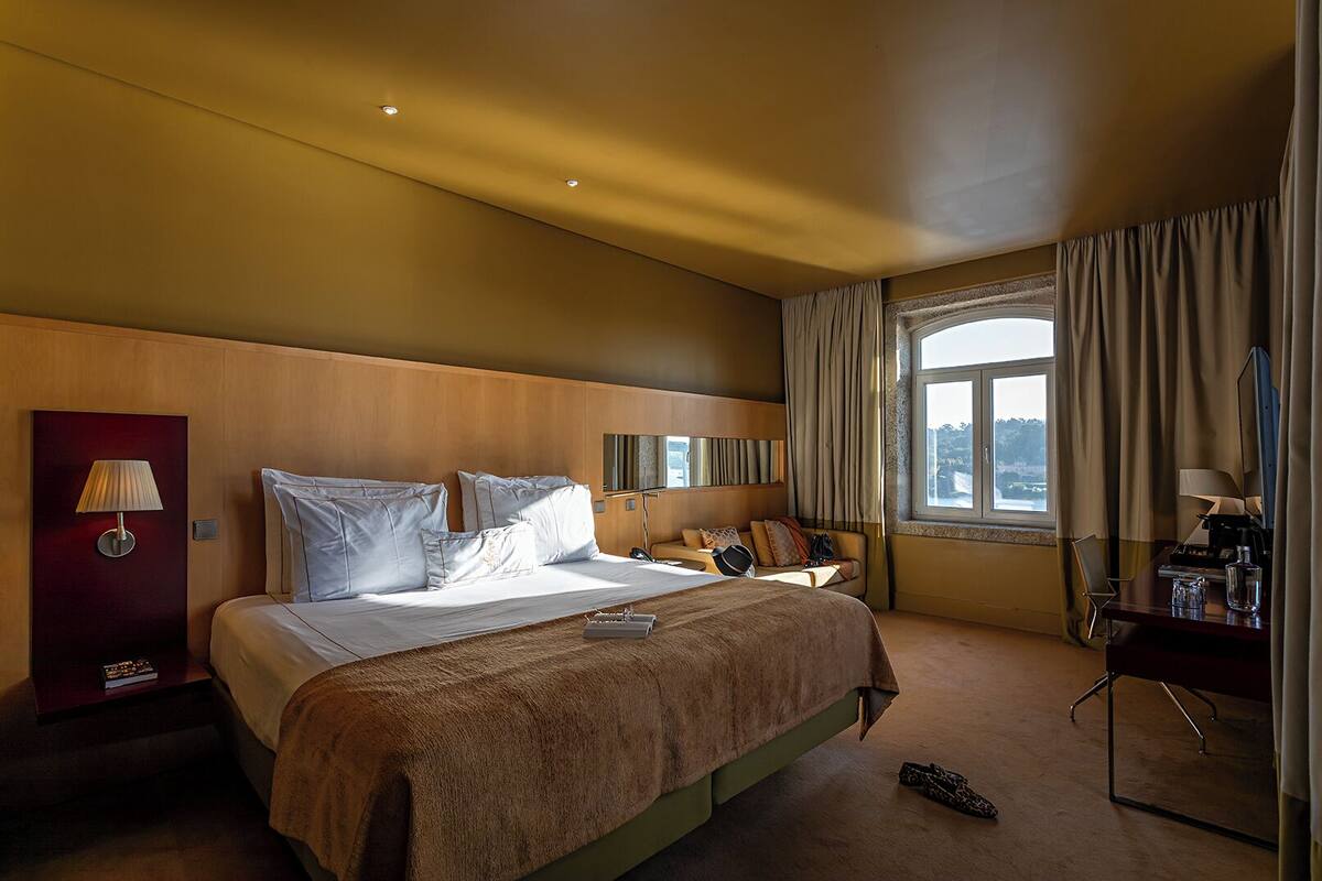 Una habitación de hotel con una cama grande, un escritorio y vistas a la ciudad.