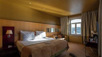 Ein Hotelzimmer mit einem großen Bett, einem Schreibtisch und Blick auf die Stadt.