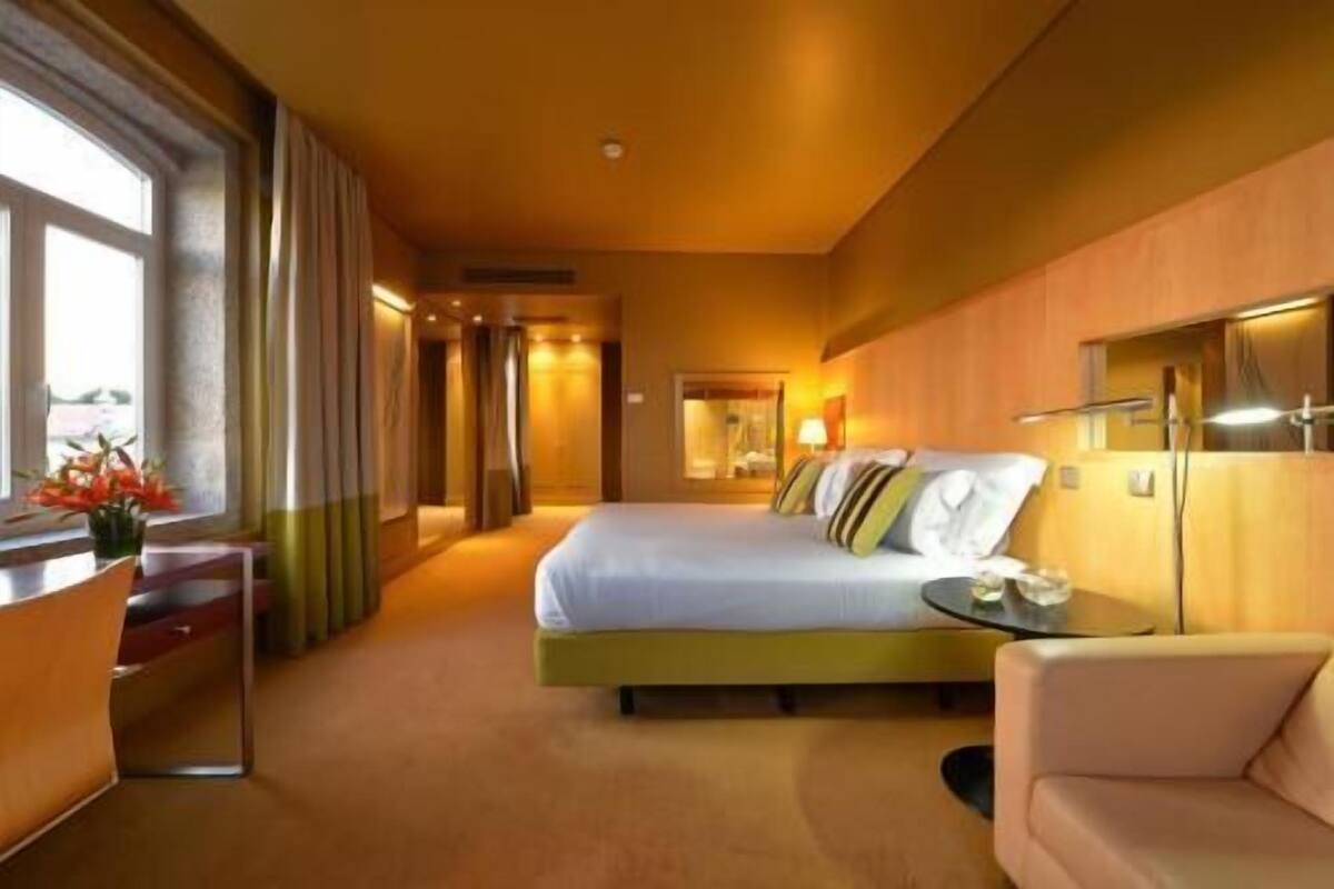 Una habitación de hotel con cama, escritorio, silla y vistas al exterior.