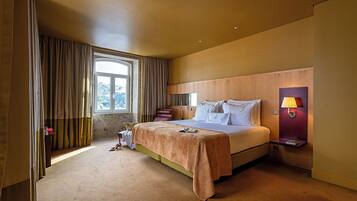 A hotel room with a bed, a nightstand with a lamp, a window with curtains, and a view of the outdoors.