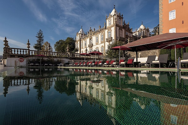Alberca techada, alberca al aire libre y sombrillas en la alberca