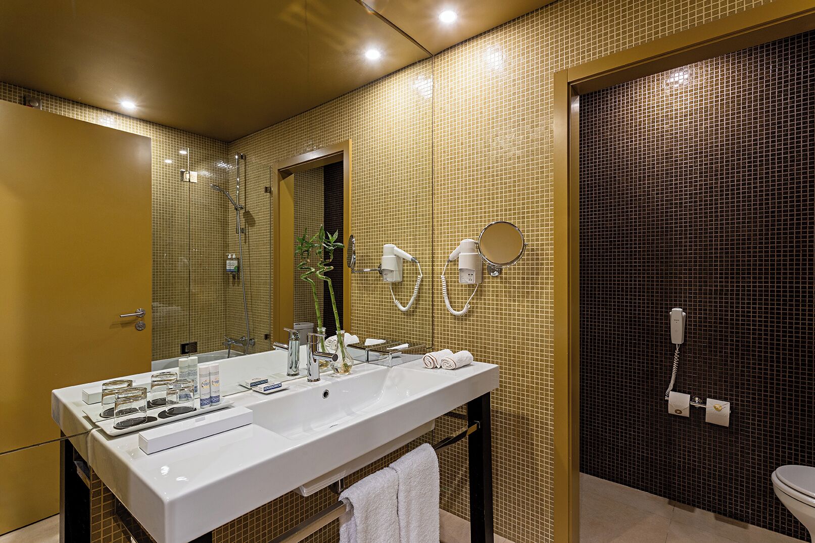 Une salle de bain moderne avec un grand lavabo blanc, un miroir, une douchette à main et des toilettes.