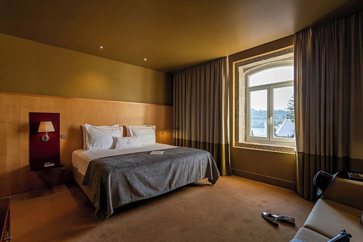 Una habitación de hotel con cama, escritorio, lámpara y vistas al exterior.