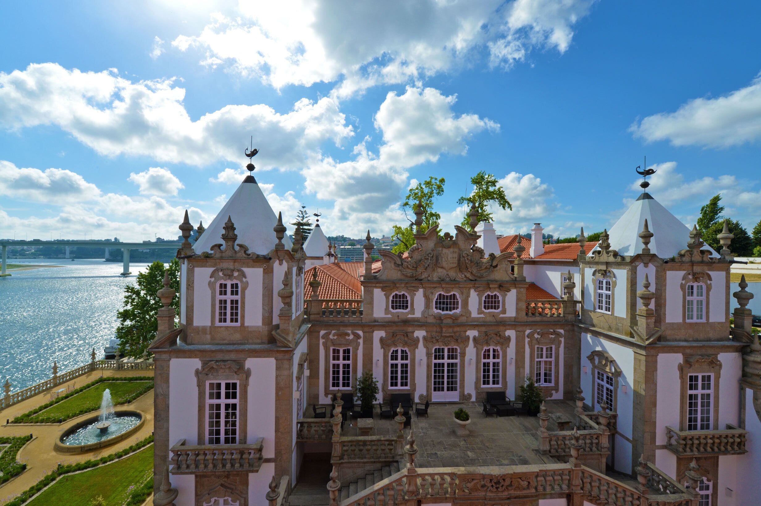 Um edifício histórico com arquitetura elaborada, um pátio e vista para o rio.
