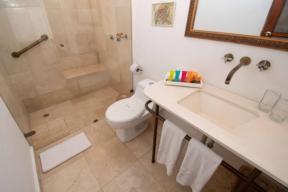 Un baño con ducha, inodoro, lavabo y toallero.