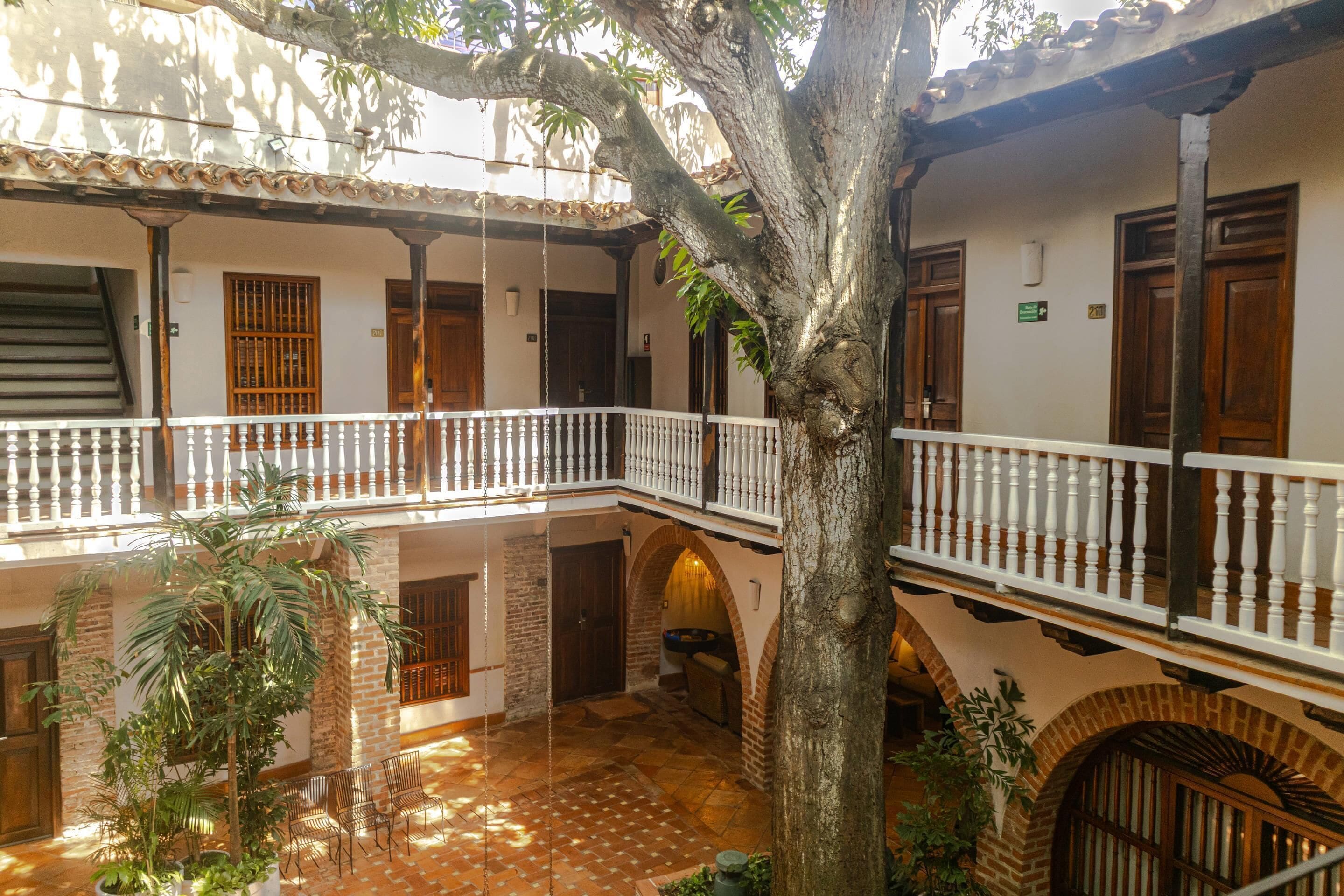 A courtyard with a tree, a staircase, and a balcony with a white balustrade.