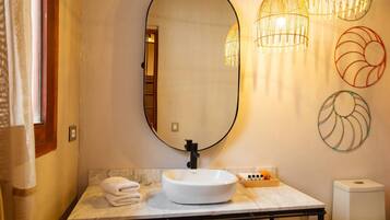 A bathroom with a white sink, a large mirror, and a toilet.