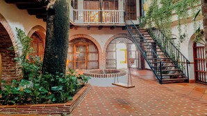 Un patio con una hamaca, piso de ladrillo y una escalera.