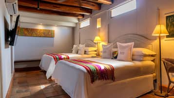 A hotel room with a large bed, two bedside tables, a wall-mounted TV, a ceiling fan, and a window providing natural light.