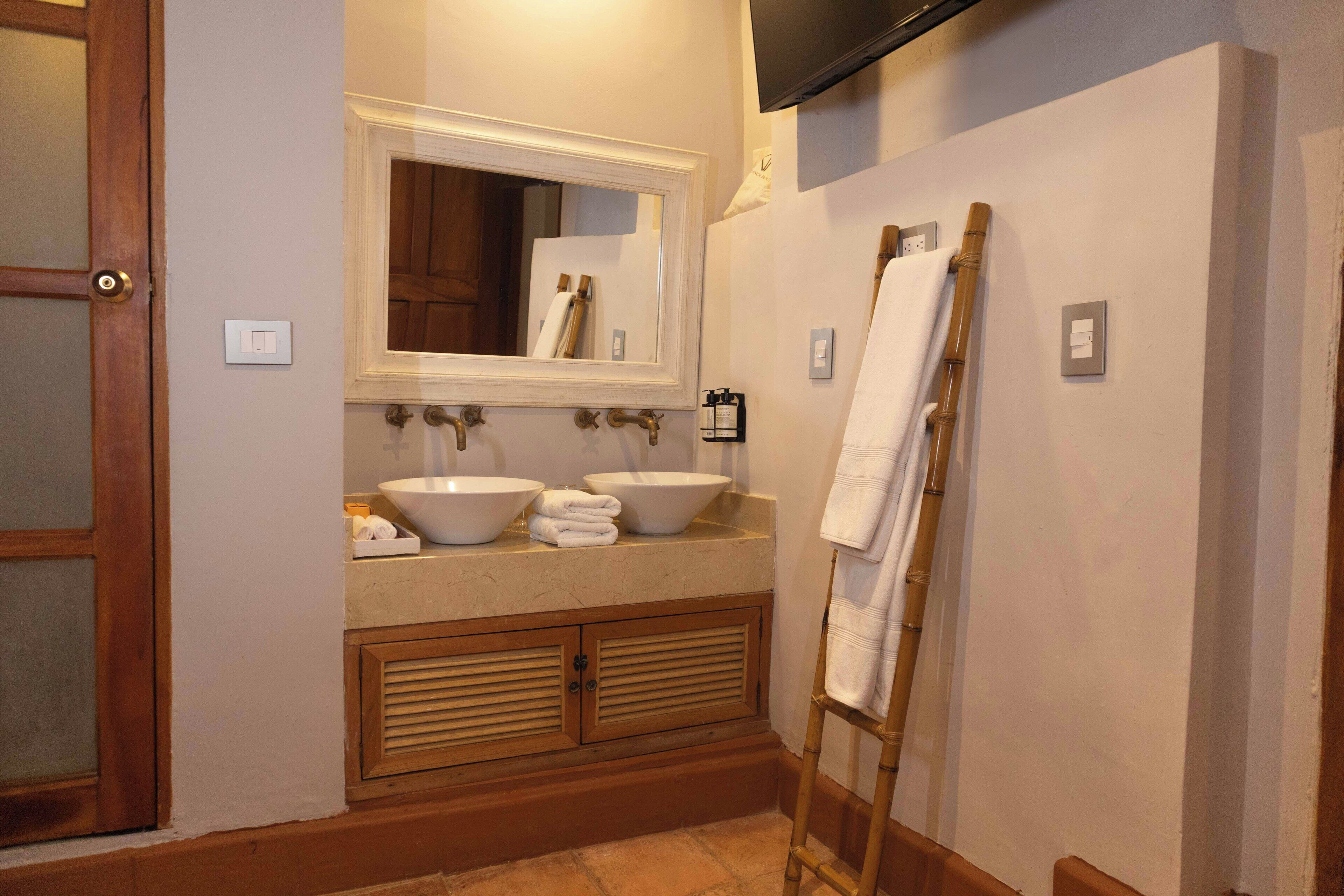 A bathroom with a double sink, a large mirror, and a wooden vanity.