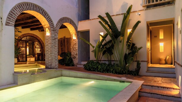 Una piscina con paseos en arco y una escalera que conduce a una puerta.