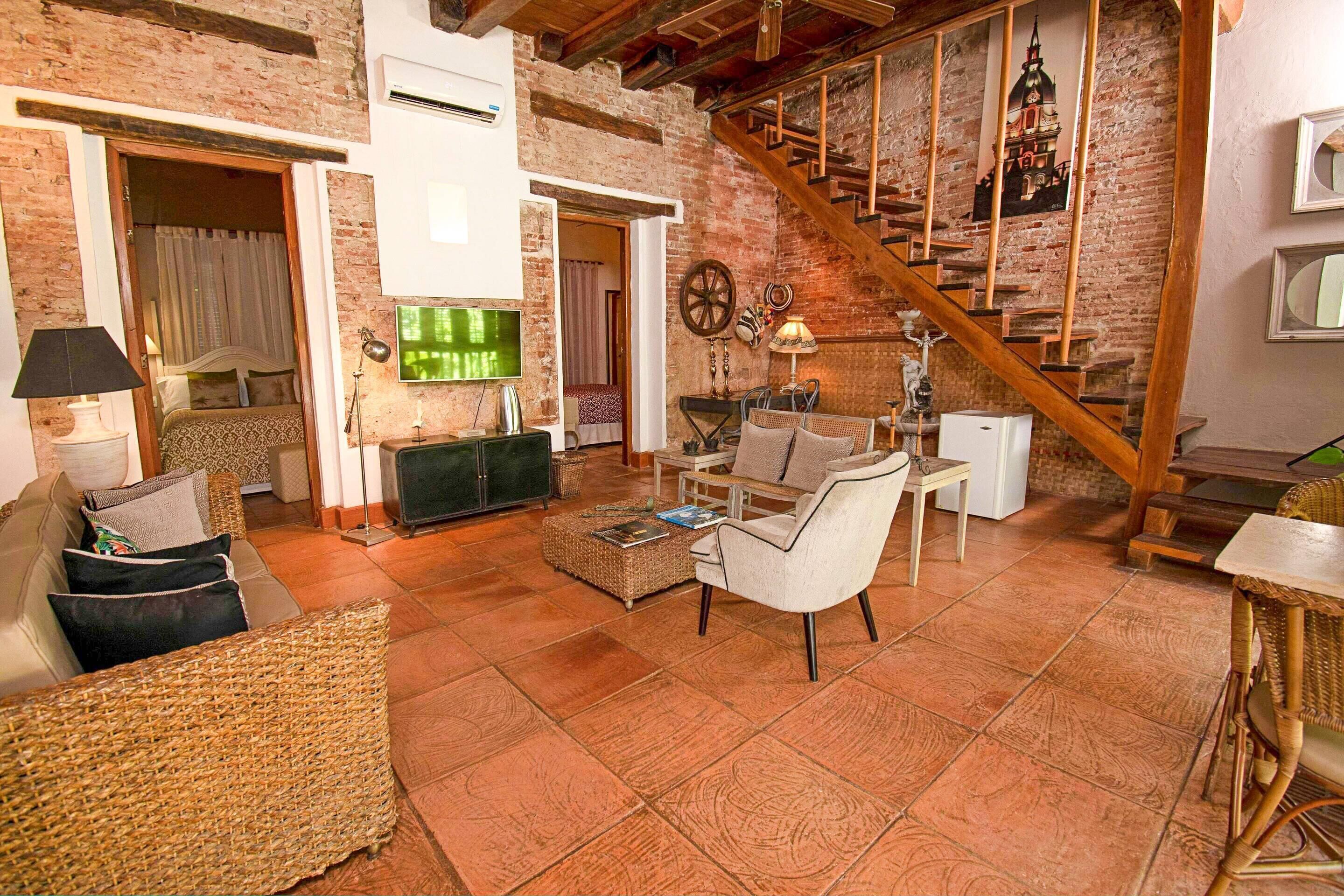 A cozy living room with wicker furniture, a television, and a staircase leading to an upper level.