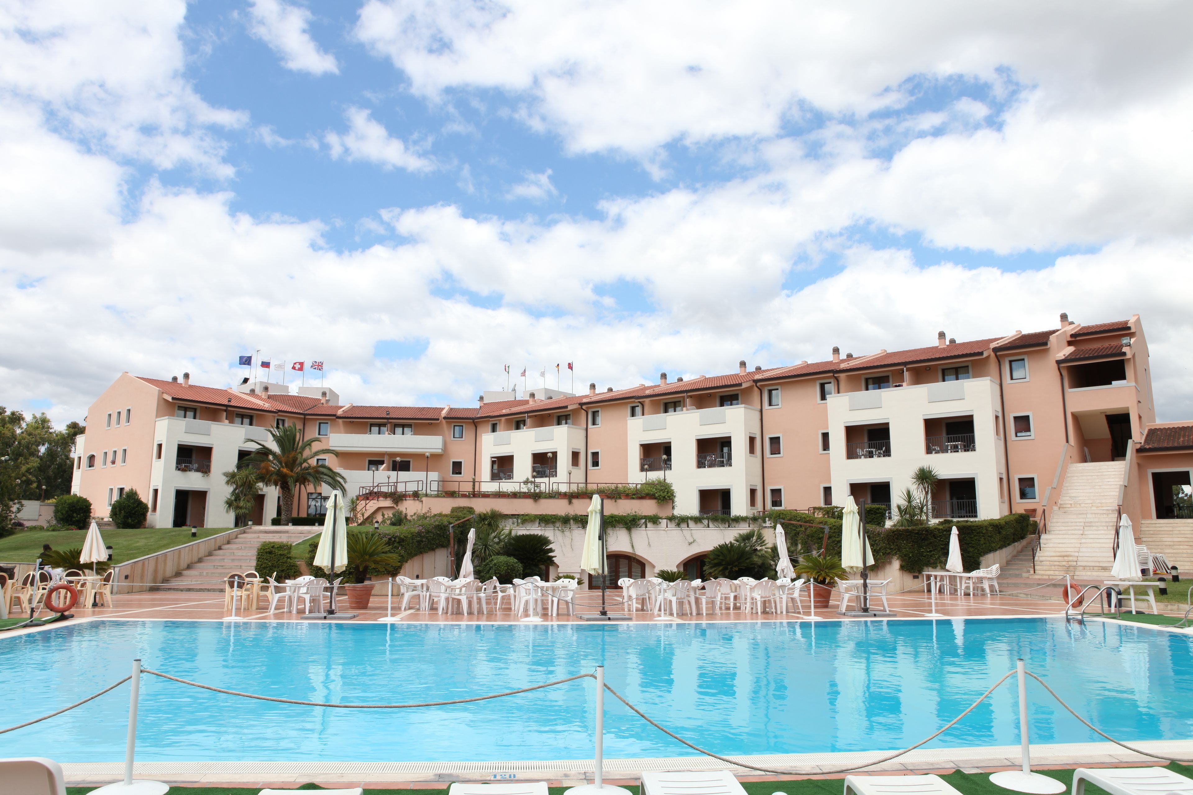 A hotel with a swimming pool, multiple balconies, and outdoor seating areas.
