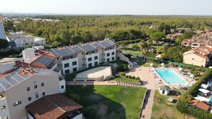 A residential building with multiple floors, solar panels on the roof, a swimming pool, and a well-maintained garden. - Heraclea Hotel Residence (Policoro)