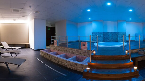 A spa area with a hot tub, seating, and a stone wall. - Heraclea Hotel Residence (Policoro)