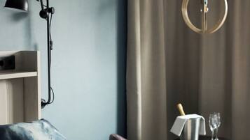 A neatly made bed with white linens, a blue pillow, and a black lamp on a bedside table.