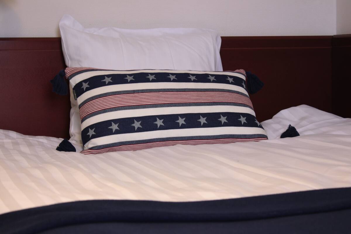 A bed with a striped pillow featuring a star pattern, a white pillow, and a dark headboard.