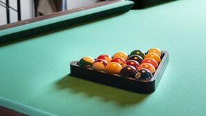 Una mesa de billar con superficie de fieltro verde y una pirámide de bolas.
