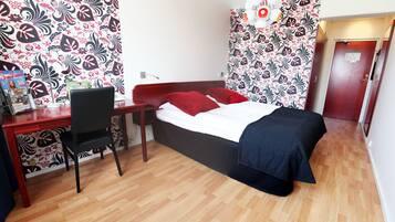 A bedroom with a bed, a desk with a chair, and a door.