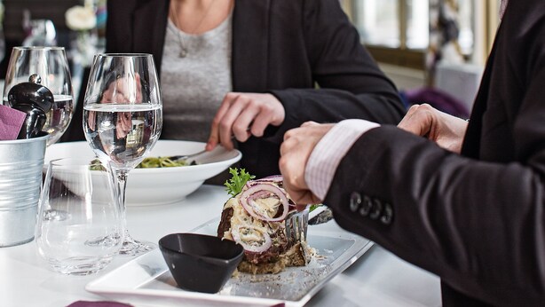 Una mesa de comedor con comida, copas de vino y un bol negro.