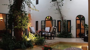 Un patio con una mesa redonda, sillas y una pequeña fuente.