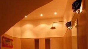 Een badkamer in moderne stijl, met gedempt licht, een ruime badkuip, een klein wastafeltje en een spiegel.