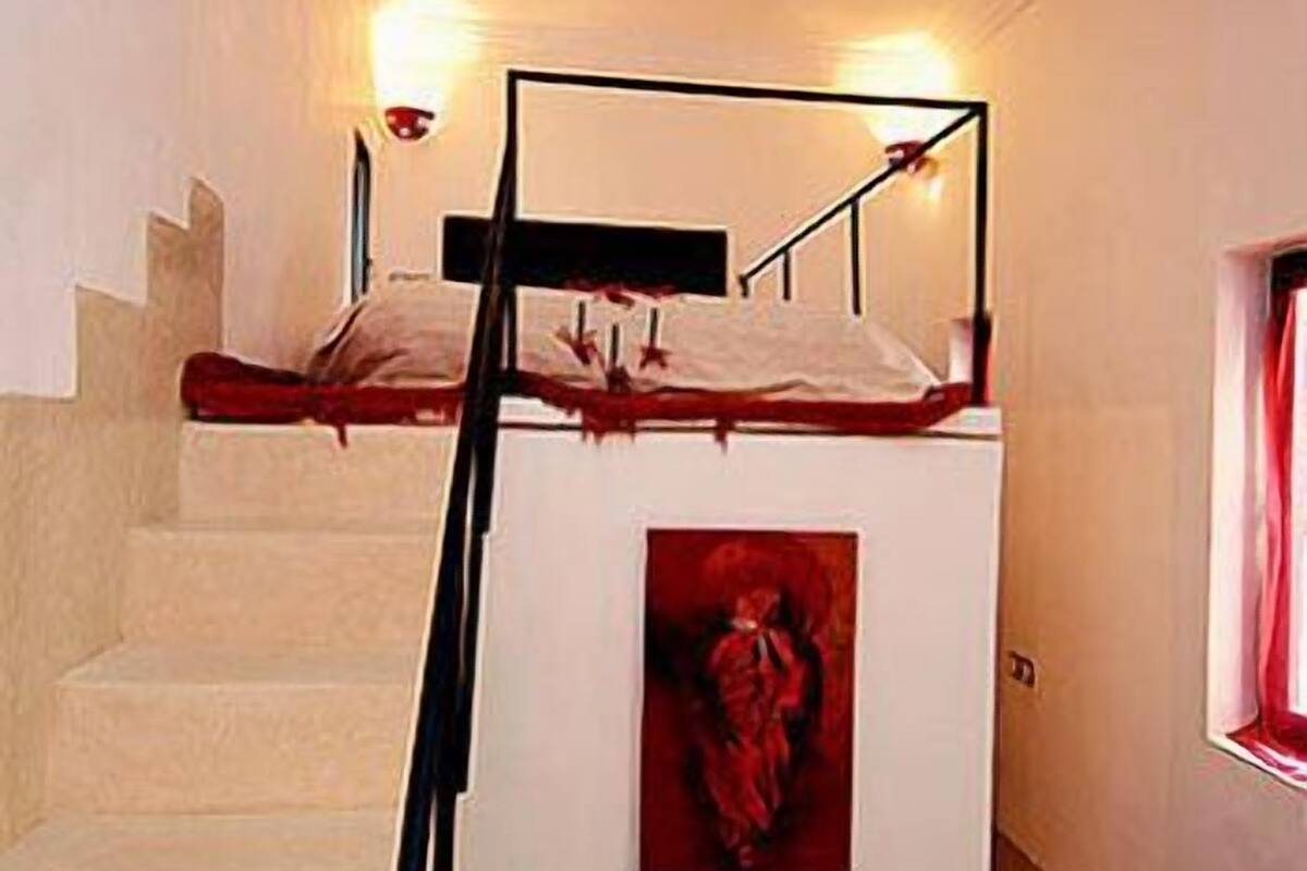 A bunk bed with a headboard, a staircase, and a framed picture on the wall.