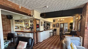 A cozy bar area with a checkered floor, leather seating, and a brick wall. - Halfway House Inn Country Lodge (Yeovil)