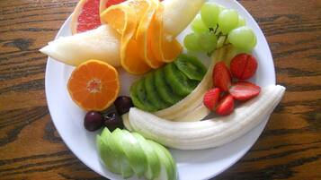 A plate of assorted fruits including grapes, strawberries, kiwi, orange slices, and banana.