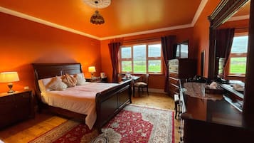 Habitación de hotel con cama, escritorio, cómoda, televisor y ventana con vista al exterior.