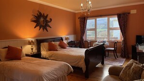Habitación de hotel con dos camas, una araña, un escritorio con silla y una ventana con cortinas.