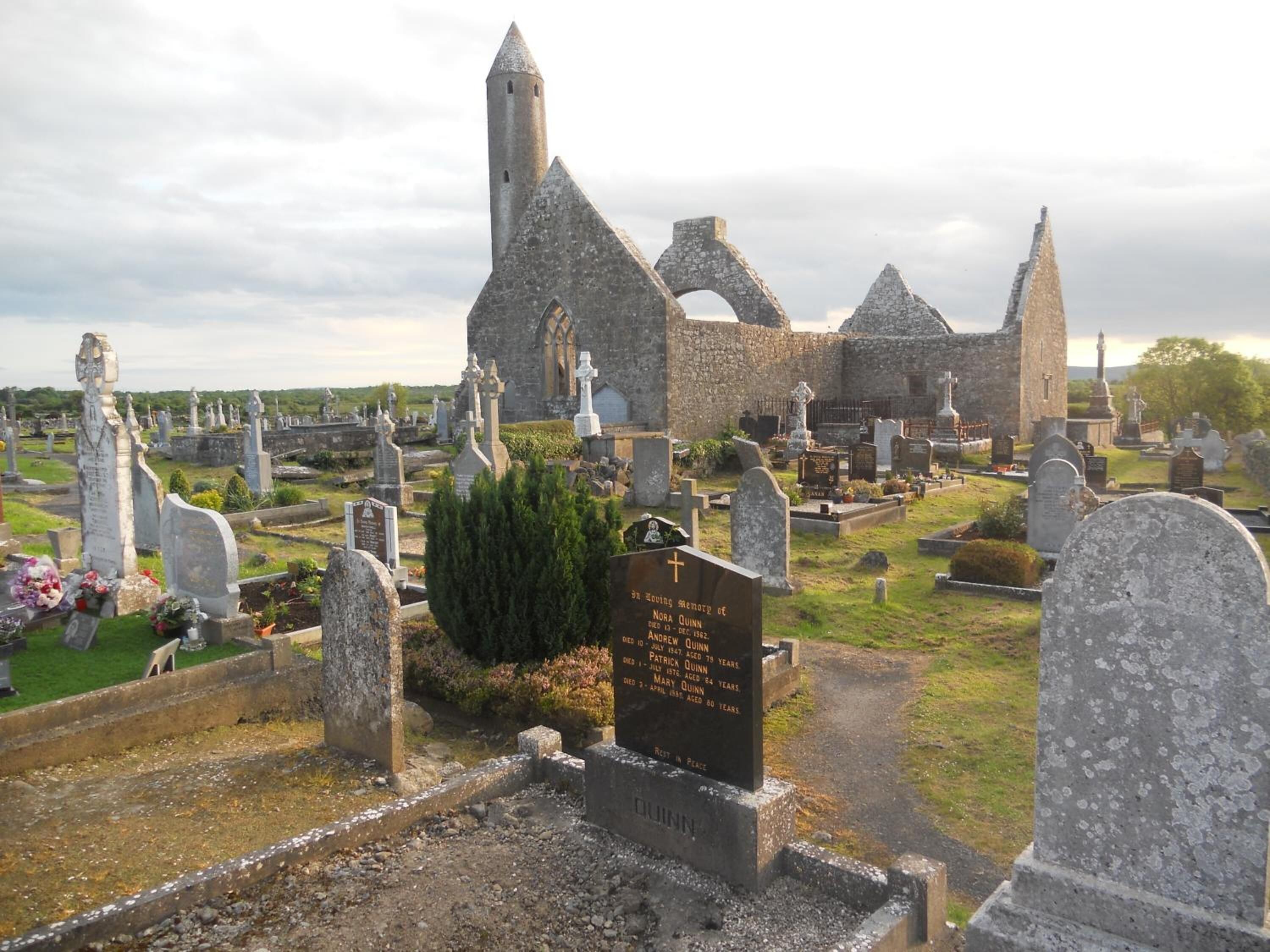 Un cementerio con lápidas de piedra y un edificio histórico de piedra al fondo.