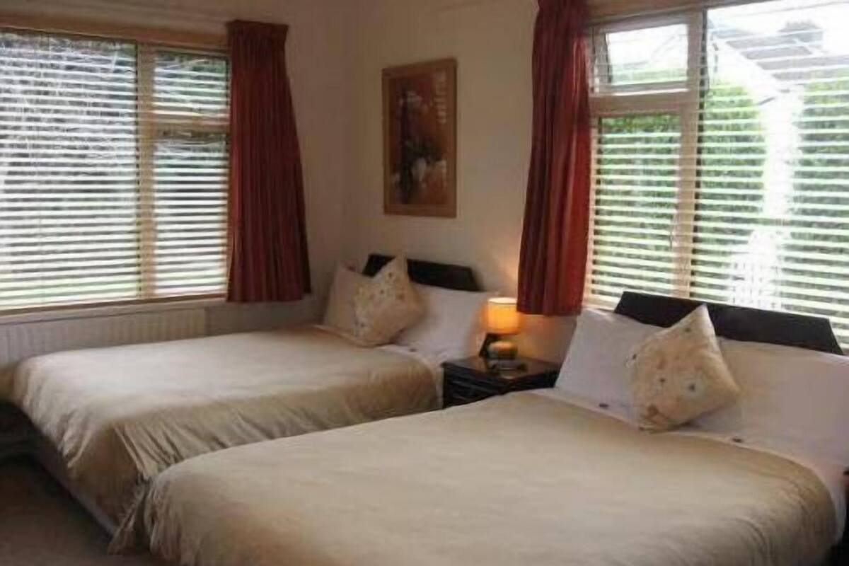 A hotel room with two beds, a nightstand with a lamp, and a painting on the wall.