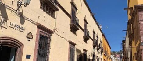 A narrow street with buildings on either side, one with a sign reading "LA MORADA HOTEL".