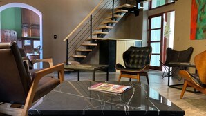 Una sala de estar moderna con una mesa de centro de mármol, sillones de cuero, una escalera y vistas al exterior.