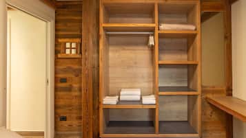 Un armario empotrado de madera con varios estantes y espacio para colgar, situado en una habitación con paneles de madera.