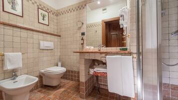 Un baño con bidé, inodoro, lavabo y cabina de ducha con mampara de vidrio.